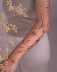 a woman's arm with tattoos on it and flowers in the foreground next to her