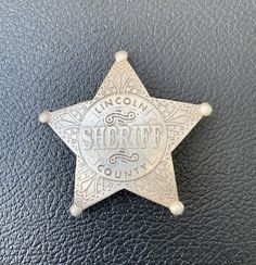 an old police badge on a black leather surface with the word lincoln sheriff written in white