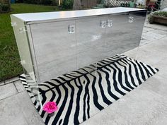 a zebra print rug on the ground in front of a mirrored cabinet with pink flower