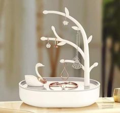 a white jewelry holder on a table with rings and necklaces hanging from the tree