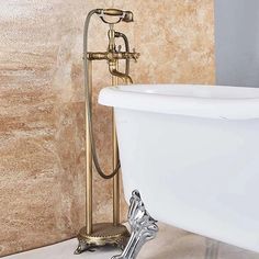 a claw foot bathtub in a bathroom with marble walls and flooring, along with a gold - plated faucet