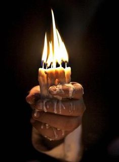 a person holding a lit candle in their hand