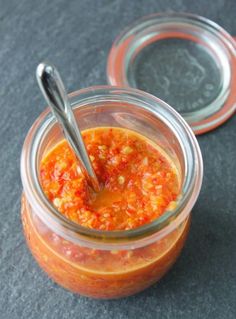 two jars filled with food sitting on top of a table next to each other and one has a spoon in it