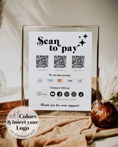 a sign that says scan to pay next to a vase with some feathers on it