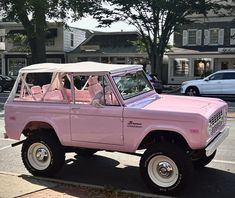 an old pink truck parked on the side of the road in front of some houses