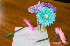 flowers in a vase sitting on top of a table next to a note that says happy mother's day