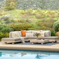 a couch sitting on top of a blue rug next to a swimming pool with trees in the background