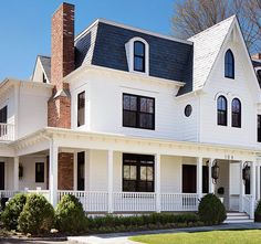 a large white house with black roof and two story dormers on the second floor