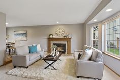 a living room filled with furniture and a fire place under a clock mounted on the wall