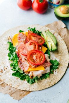 an uncooked tortilla with tomatoes, lettuce and ham