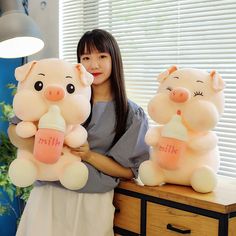 a woman holding two stuffed pigs with milk in their hands