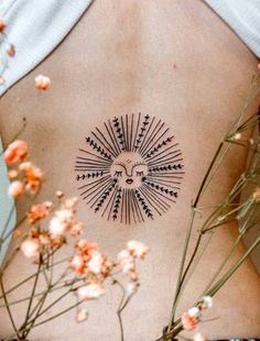 the back of a woman's stomach with an intricate sun tattoo on her left side