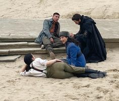 four people sitting on the sand near steps