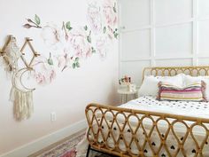 a bed with white sheets and pink flowers on the wall