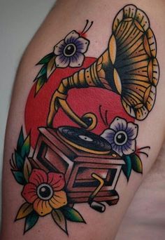 a tattoo with an old record player and flowers on it