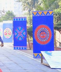 a man walking down a sidewalk next to blue and red banners with designs on them