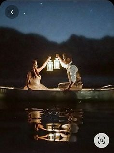 a man and woman in a boat holding a lantern