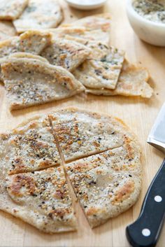 homemade pita bread cut into four pieces on a cutting board with a knife next to it