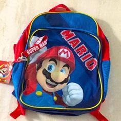 a blue and red backpack with a mario character on the front, sitting on a white surface