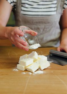 a person is sprinkling sugar on to cubes of food sitting on a table