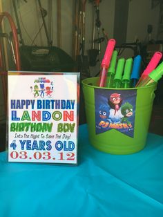 a birthday sign sitting on top of a table next to a bucket filled with markers