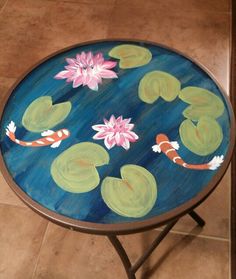 a painted table with water lilies and koi fish in the pond on it