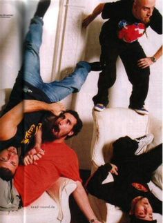 a group of men laying on top of each other in front of a white wall