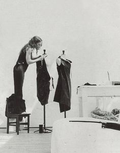 a black and white photo of a woman looking at clothes on a mannequin