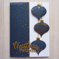 a christmas card with two ornaments hanging from it's side and the words christmas wishes written in gold