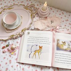 an open book sitting on top of a table next to a cup and saucer