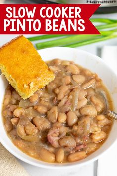 a white bowl filled with beans next to a piece of bread