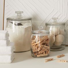 several glass jars filled with different types of wooden dows and cotton swabs