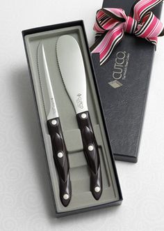 two knives in a gift box with a pink ribbon around the handle and black handles