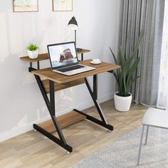 a laptop computer sitting on top of a wooden desk next to a potted plant