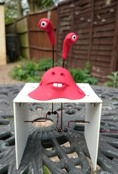 two red birds sitting on top of a white box with wires attached to the sides