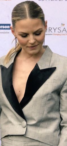 the woman is looking down at her cell phone while wearing a gray suit and black tie