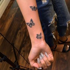 a woman's arm with three butterflies tattooed on the back of her left arm