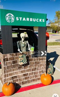 a starbucks skeleton sitting in the back of a car with pumpkins on the side