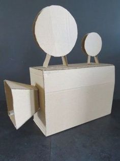 an open cardboard box with two mirrors on the top and one in the middle, sitting on a black floor