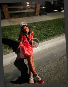 a woman in a red dress sitting on the sidewalk