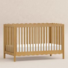 a small wooden crib with white sheets on the bottom and sides, against a beige wall