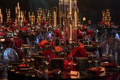 a table is set up with red flowers and place settings for an event or celebration