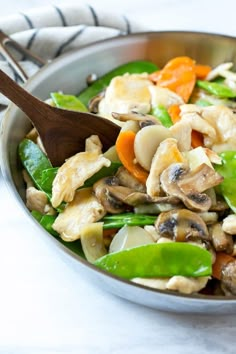 a salad with mushrooms, carrots and spinach in a silver bowl on a marble table