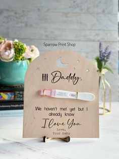 a wooden sign with two toothbrushes in it on a table next to flowers