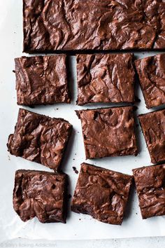 chocolate brownies cut into squares on top of a sheet of parchment paper, ready to be eaten