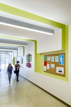 two people walking down a hallway with posters on the wall