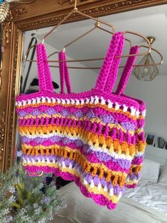 a crocheted bag hanging from a clothes hanger in front of a mirror