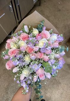 someone holding a bouquet of pink and white flowers in their left hand on the floor