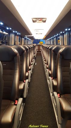 the inside of an airplane with rows of seats on each side and lights above them