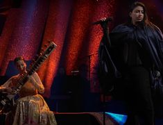 two people on stage with one holding a guitar